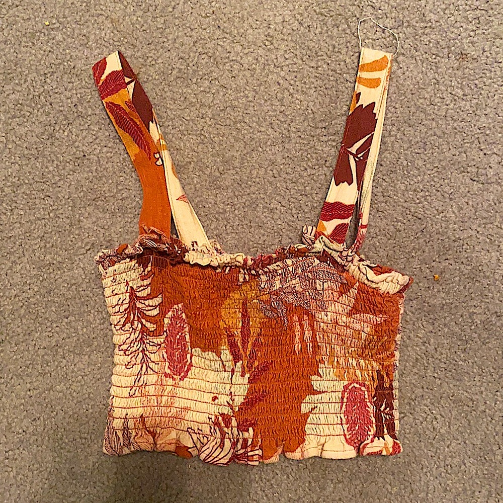 A ruched crop top that has a tropical floral pattern and has adjustable straps.